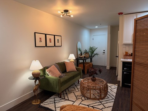 A living room with a green couch, a wicker table, and a rug.