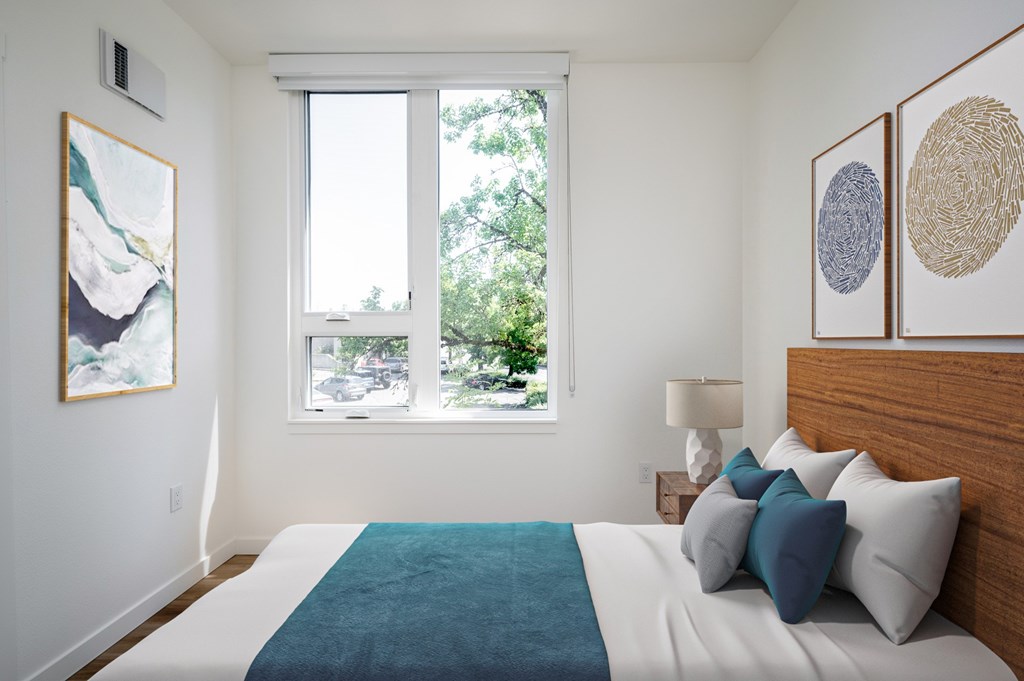 The Wes Gresham Oregon Apartments A bedroom with a large bed and a window overlooking a tree-filled street.