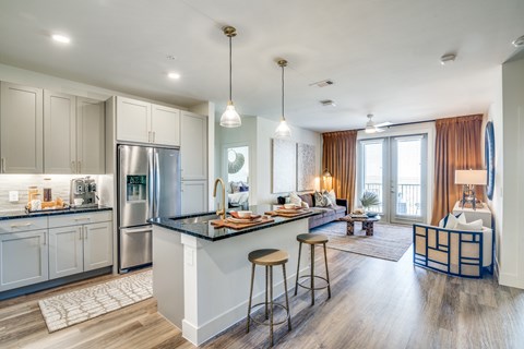 A modern kitchen with a bar area and a living room with a couch.