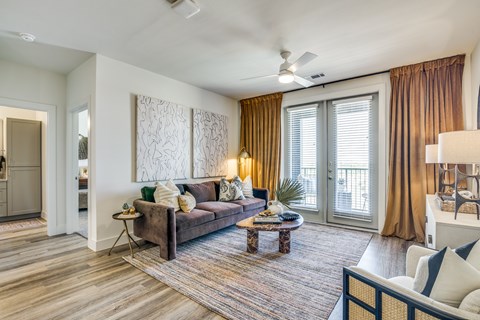 A living room with a brown couch and a rug.