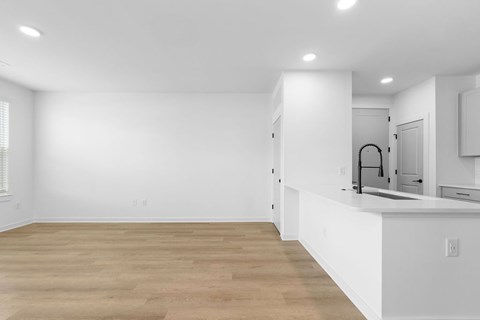 A kitchen with white cabinets and a wooden floor.
