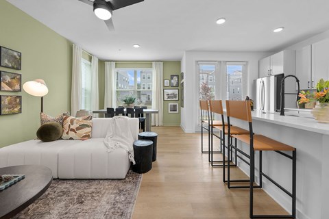 A modern living room with a white couch and a kitchen area in the background.