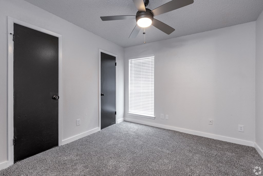 an empty room with a ceiling fan and a door to a closet