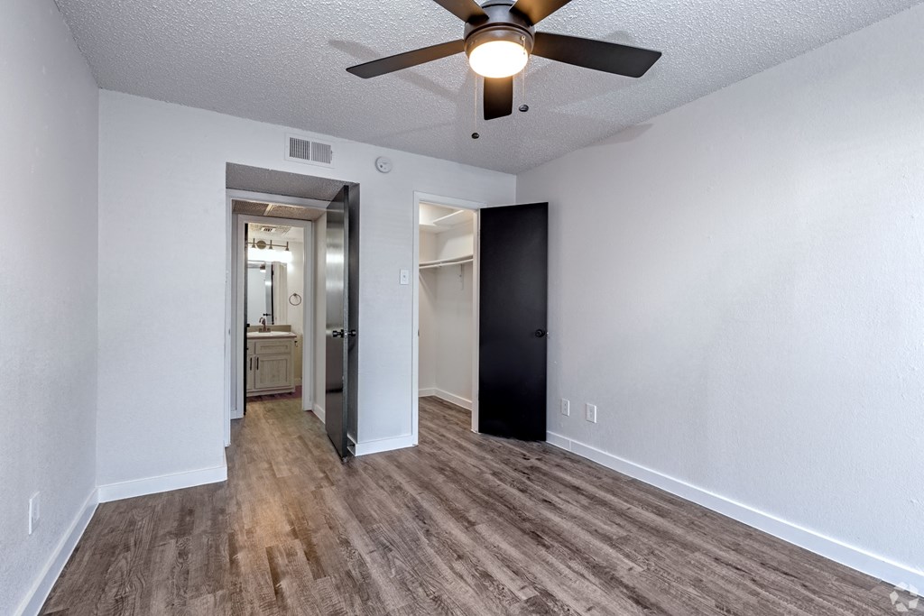 an empty living room with a ceiling fan and a door to a bathroom