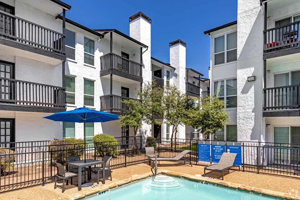 the baxter apartments feature a pool and patio area with an umbrella