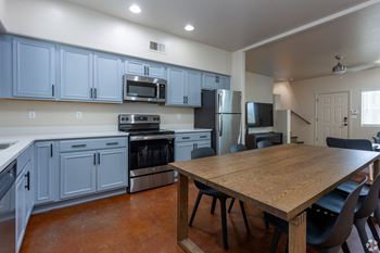 A kitchen with a table and chairs in the foreground.