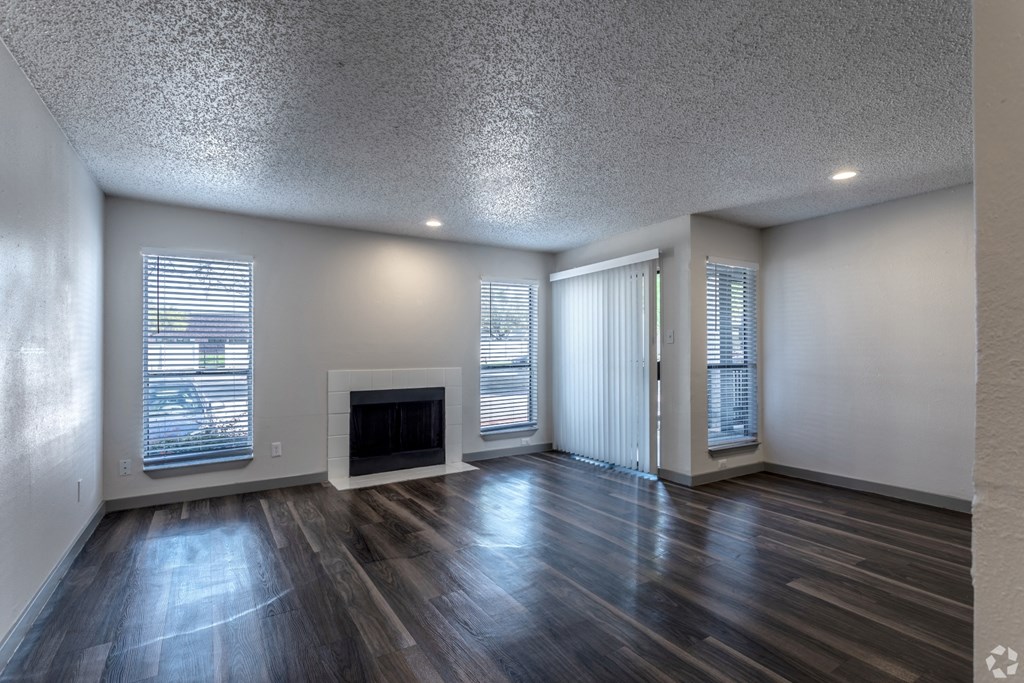 an empty living room with a fireplace and wooden floors