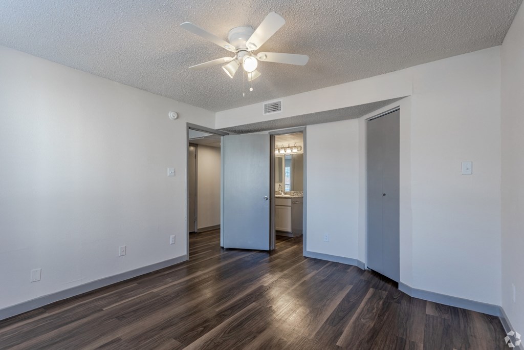 an empty living room with a ceiling fan and a bathroom