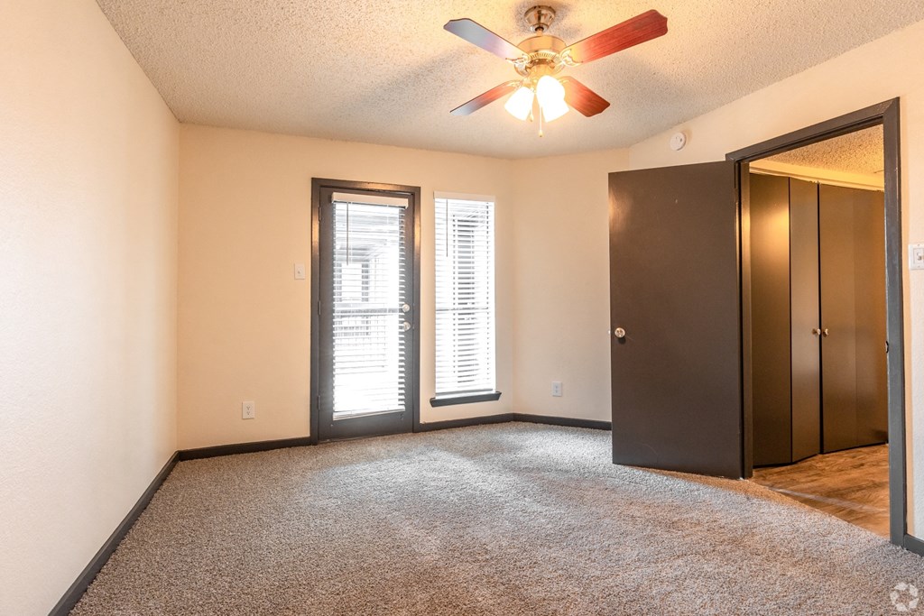 an empty living room with a ceiling fan and a door to a closet