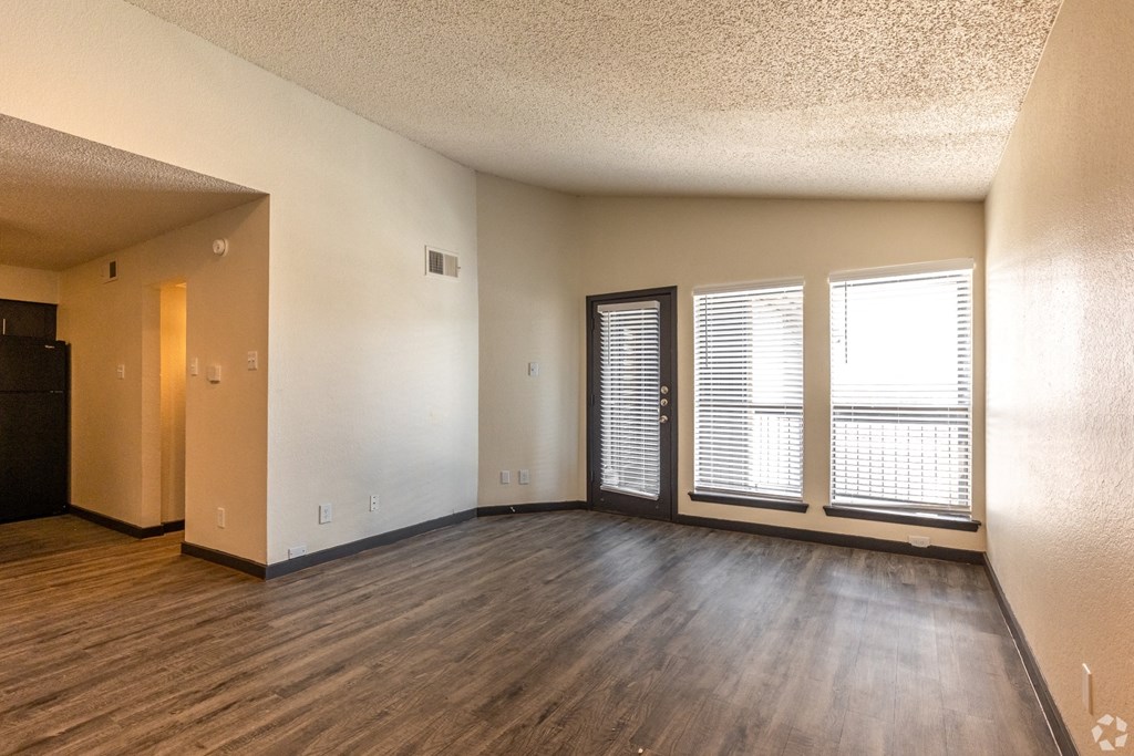 an empty living room with wood floors and a window