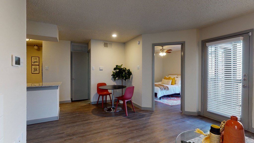 a living room and kitchen with a bedroom in the background