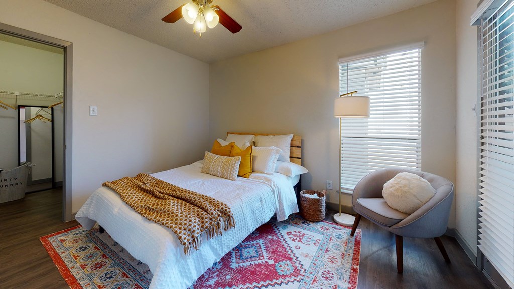a bedroom with a bed and a chair and a ceiling fan