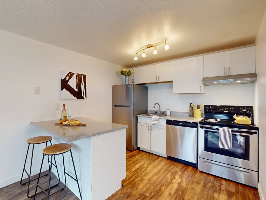 a kitchen with stainless steel appliances and a counter with two stools