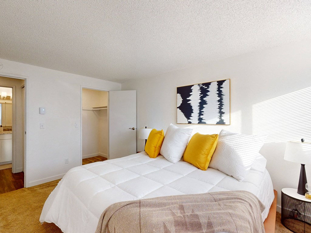 a bedroom with a large white bed and yellow pillows