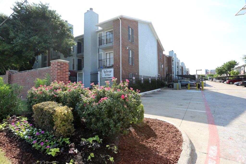 an apartment building with a sidewalk and flowers in front of it