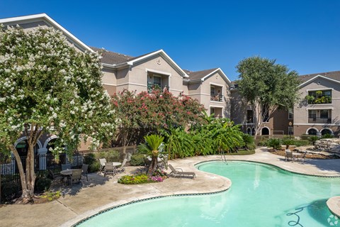 A swimming pool surrounded by a landscaped garden and residential buildings.