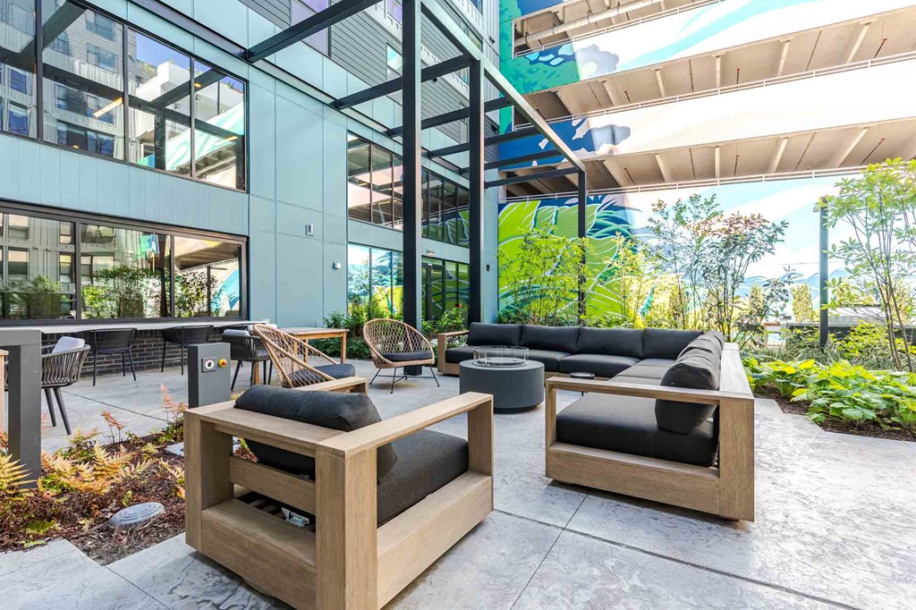 A modern outdoor seating area with wooden furniture and a glass building in the background.