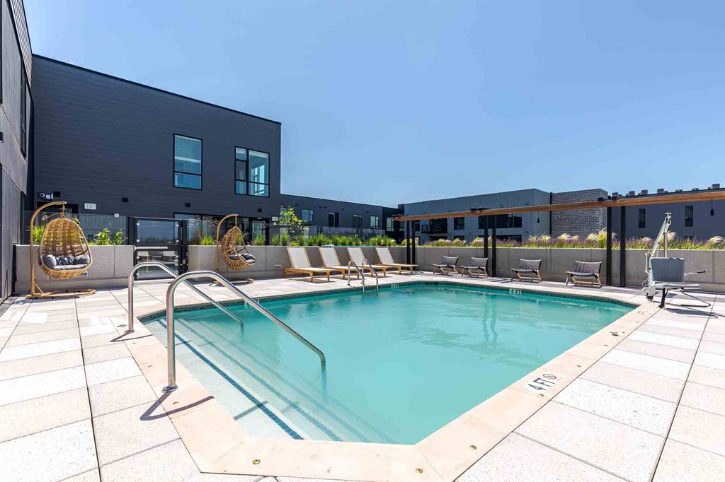 A modern pool area with a clear blue pool and lounge chairs.
