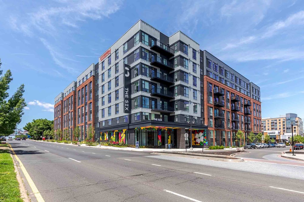 A modern multi-story building with a mix of red, grey, and black exterior.