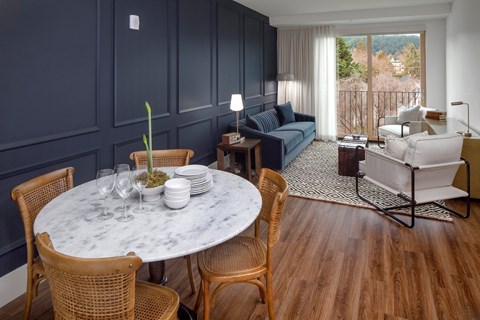 A living room with a round marble table surrounded by chairs.