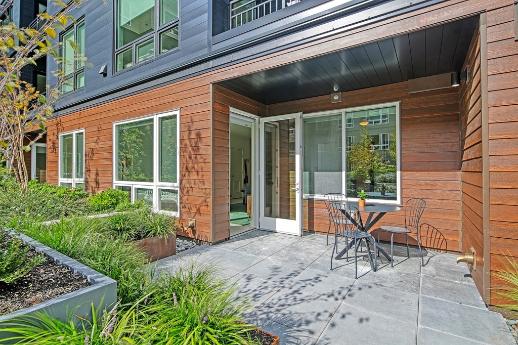 a patio with a table and chairs in front of a building