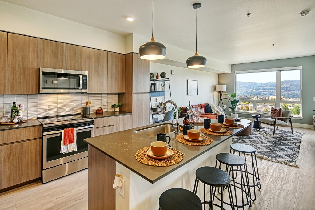 a kitchen with a large island with a breakfast bar and a living room with a couch and