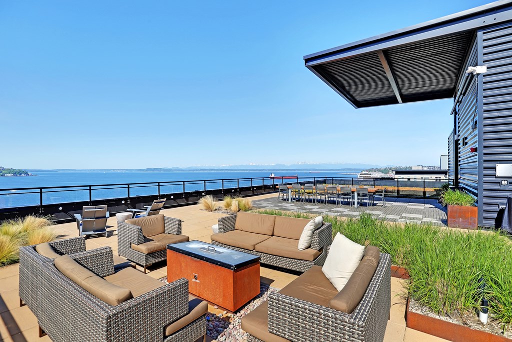 a large terrace with couches and a fire pit with a view of the ocean