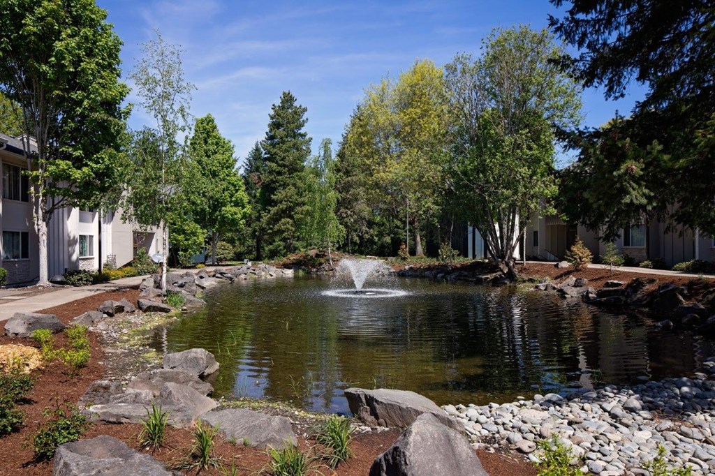 a fountain in the middle of a pond with trees in the background