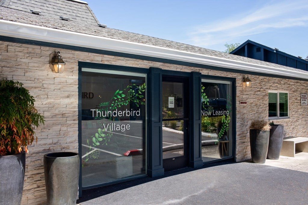 a brick building with glass doors and a sign that reads thunderbird village