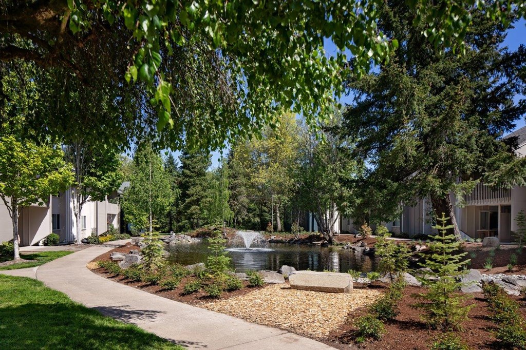 a pond with a fountain in front of a building
