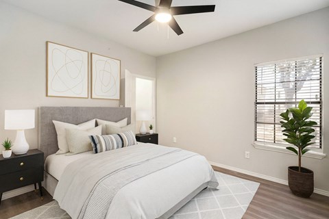 A bedroom with a large bed, a ceiling fan, and two wall lamps.