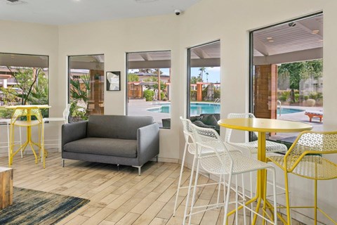 a living room with yellow tables and chairs and a pool