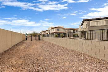 A gravel driveway leads to a house with a metal fence on one side.