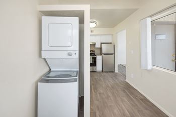 A white dishwasher is in a kitchen with wood flooring.