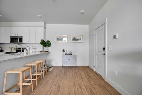 A kitchen with white cabinets and wooden floors.