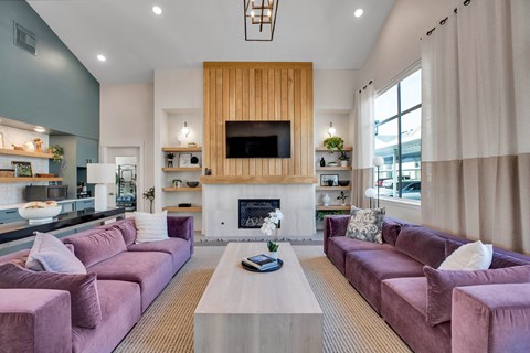 A living room with a fireplace and a television mounted above it.