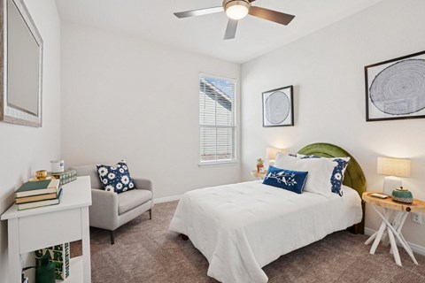 A bedroom with a white bed and a grey armchair.
