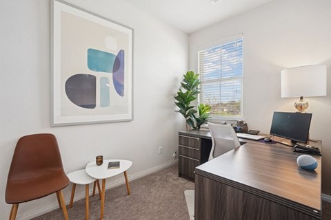 A modern office with a brown chair and a framed abstract art on the wall.