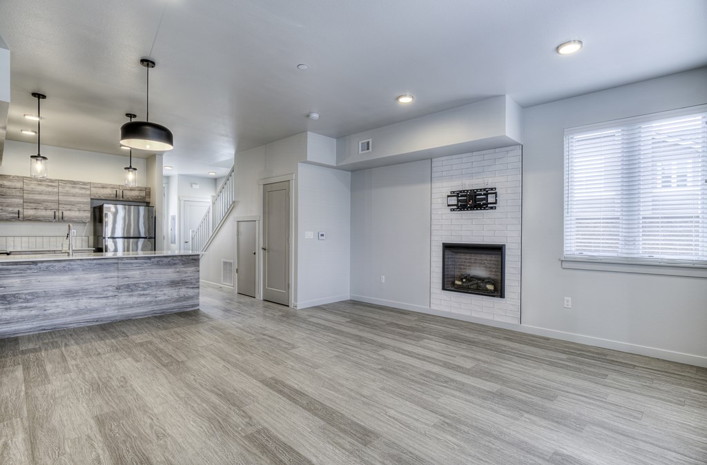 A spacious living room with a fireplace and a staircase.