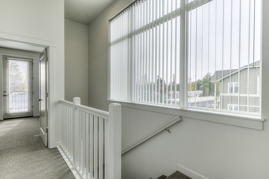 A white room with a carpeted floor and a staircase with white railings.