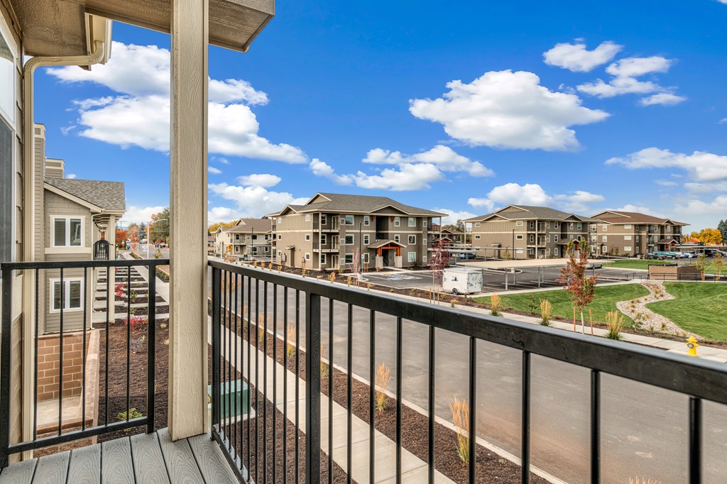 A balcony overlooks a street with houses and trees.