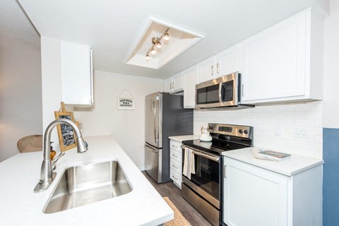 a white kitchen with stainless steel appliances and a sink