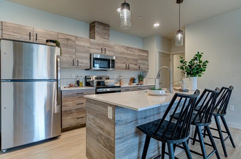 a kitchen with stainless steel appliances and a island with chairs