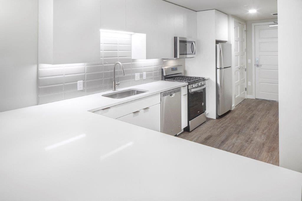 a white kitchen with a sink and a refrigerator