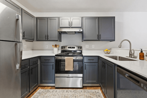 A modern kitchen with dark grey cabinets and stainless steel appliances.