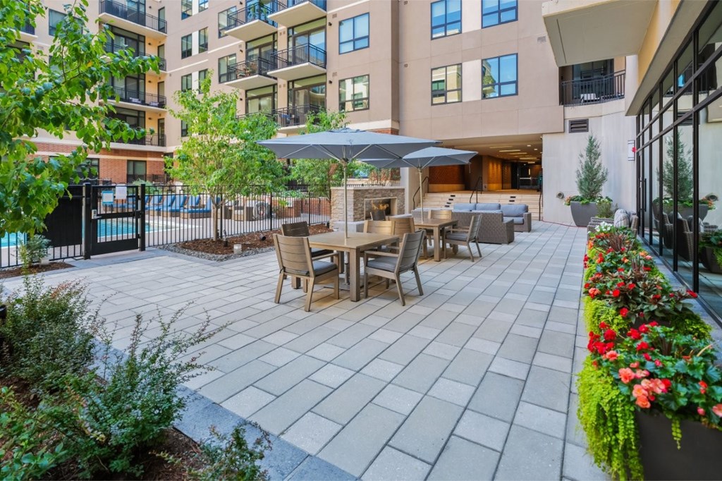 A patio with a table and chairs is surrounded by a fence and buildings.