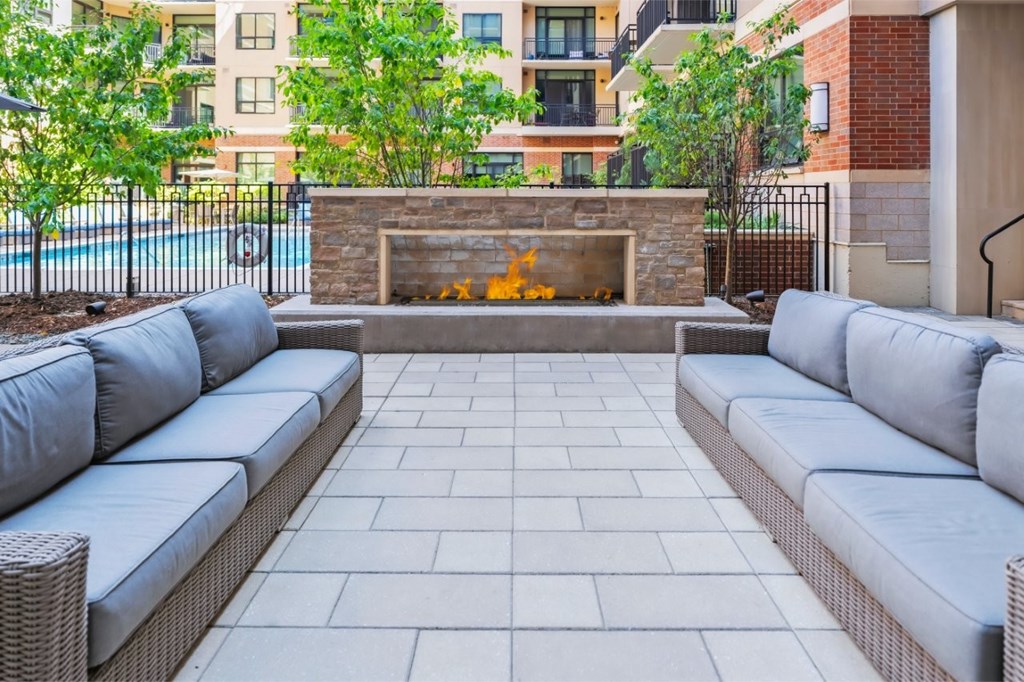 A patio with a grey couch and a fireplace.