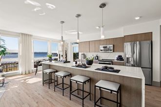 Vela Apartments kitchen with a large island with stools and a large window with a view of Lake Washington