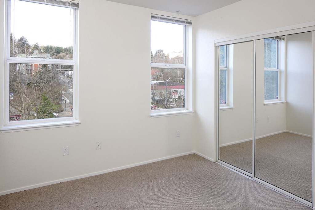Collins Circle Apartment Portland  bedroom with a large window and a mirrored closet