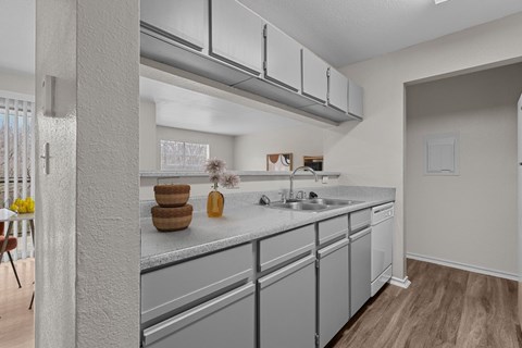 A kitchen with a white counter top and grey cabinets.